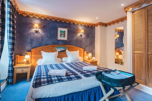 a bedroom with a large bed with a suitcase on it at Hôtel Le Bois Joli in Cauterets