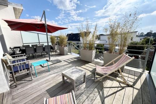 un patio avec des chaises et un parasol sur le toit dans l'établissement Magnifique maison d’architecte - Plages à pied, à Larmor-Plage