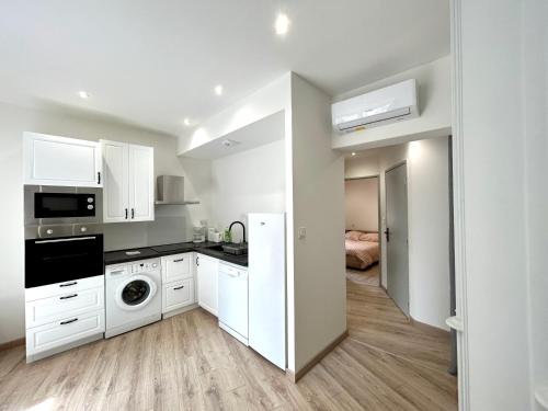 une cuisine avec des armoires blanches et une laveuse et une sécheuse dans l'établissement Joli T2 Plein Coeur du Centre Historique, à Avignon