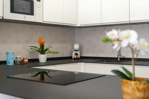 a kitchen with white cabinets and a counter top with flowers at Sunset Vibes Mijas in La Cala de Mijas