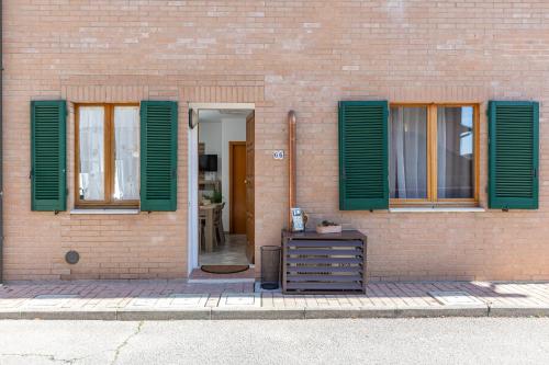 a brick building with green shuttered windows and a dresser at Il Cammino in San Quirico dʼOrcia