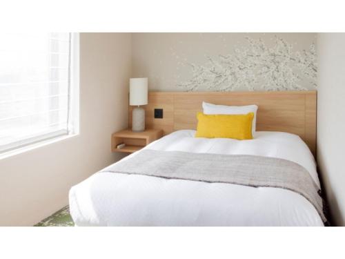 a bedroom with a white bed with a yellow pillow at Hotel Terrace the Garden Mito - Vacation STAY 75702v in Mito