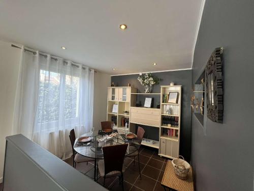 une salle à manger avec une table en verre et une étagère à livres dans l'établissement Le Beau Séjour Appartement - Elégant et Spacieux- Proche Aéroport, à Beauvais