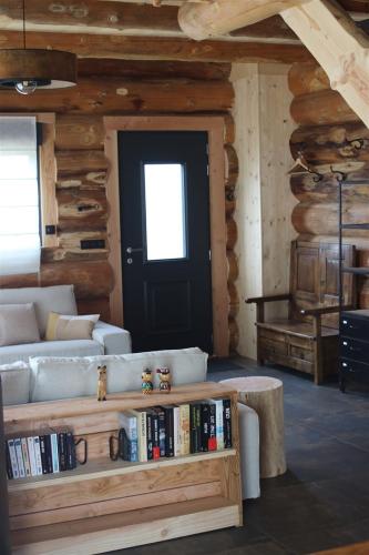 a living room with a couch and a table with books at Auvergne, Chalet cinq étoiles en fuste, 6 personnes avec spa, campagne et chevaux in Saint-Jean-en-Val