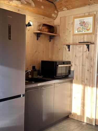 a kitchen with a refrigerator and a microwave at Auvergne, Chalet cinq étoiles en fuste, 6 personnes avec spa, campagne et chevaux in Saint-Jean-en-Val