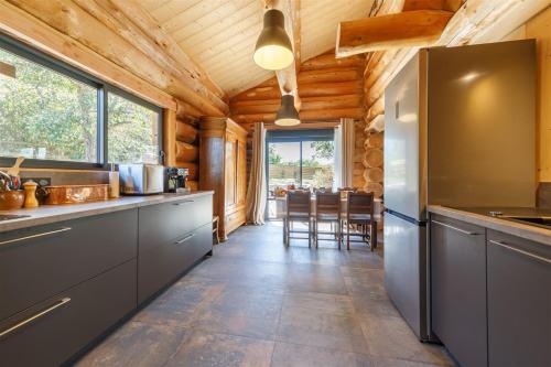 a kitchen with a refrigerator and a dining room at Auvergne, Chalet cinq étoiles en fuste, 6 personnes avec spa, campagne et chevaux in Saint-Jean-en-Val
