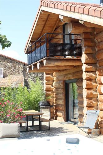 a wooden building with a table and a balcony at Auvergne, Chalet cinq étoiles en fuste, 6 personnes avec spa, campagne et chevaux in Saint-Jean-en-Val