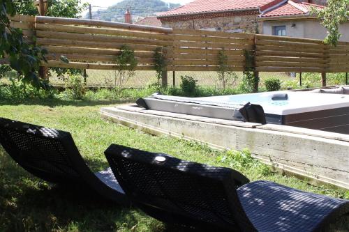 a backyard with two chairs and a hot tub at Auvergne, Chalet cinq étoiles en fuste, 6 personnes avec spa, campagne et chevaux in Saint-Jean-en-Val