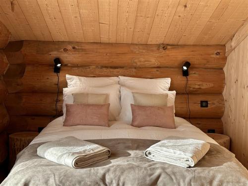 a bed in a wooden room with two pillows on it at Auvergne, Chalet cinq étoiles en fuste, 6 personnes avec spa, campagne et chevaux in Saint-Jean-en-Val