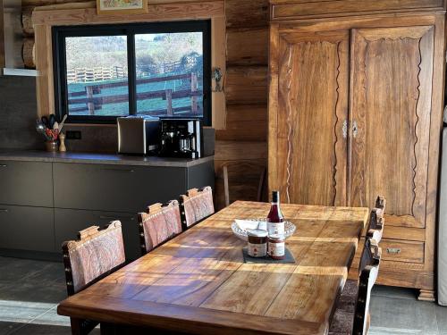 a wooden table with chairs and a bottle of wine on it at Auvergne, Chalet cinq étoiles en fuste, 6 personnes avec spa, campagne et chevaux in Saint-Jean-en-Val