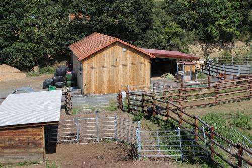 a wooden barn with a fence in a field at Auvergne, Chalet cinq étoiles en fuste, 6 personnes avec spa, campagne et chevaux in Saint-Jean-en-Val