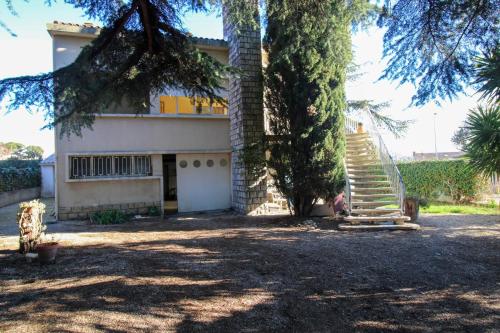 une maison avec un arbre et des escaliers en face de celle-ci dans l'établissement Clos Garrigue, à Poulx