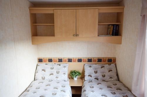a bedroom with two beds and a cabinet above them at Bella May Mobile Home in Ballintra