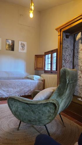 a living room with a green chair and a bed at Stirpe nel Bosco - Fiocco in Montevettolini