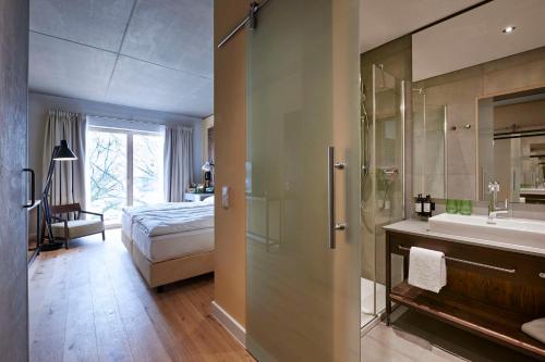 a bathroom with a shower and a bed and a sink at Hotel FREIgeist Einbeck BW Signature Collection in Einbeck