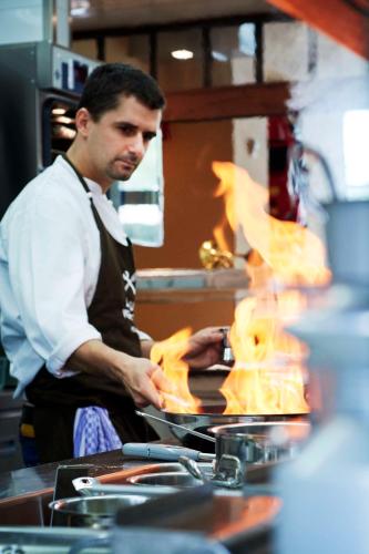 a man in a kitchen preparing food in a pan at Hotel FREIgeist Einbeck BW Signature Collection in Einbeck