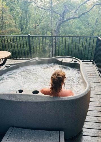 a woman in a hot tub on a deck at Firefly2 - luxury lakeside treehouse with hot tub in Eureka Springs