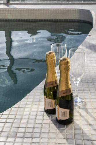 two champagne bottles and wine glasses next to a swimming pool at Hotel Innovo in Rosario