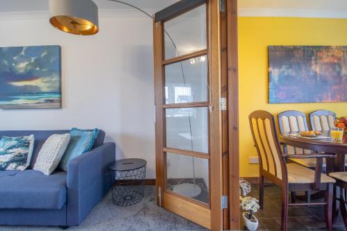 a living room with a blue couch and a table at Ideal Contractor Stay 2-Bed Near Glasgow Fort in Garthamlock