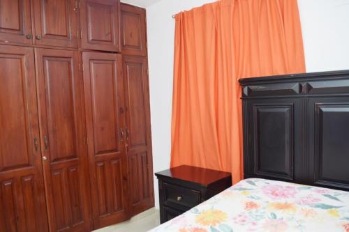 a bedroom with a bed and some wooden cabinets at Relax in this apartment in Santiago de los Caballeros