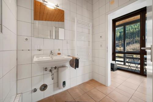 a white bathroom with a sink and a window at Luxus-Gästehaus mit Sauna, Kamin & exklusivem Paarbereich in Neubulach