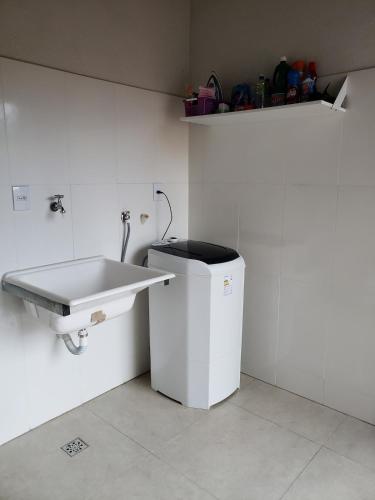 a white bathroom with a sink and a trash can at Casa em Capitolio-MG in Capitólio