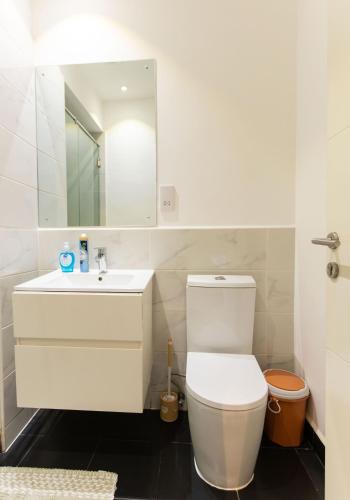 a white bathroom with a toilet and a sink at Central Studio Suite at Embassy Gardens in Accra
