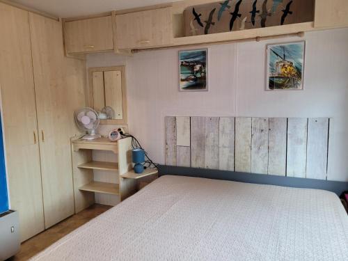 - une chambre avec un lit et des photos sur le mur dans l'établissement Mobilhome Châlet 4 personnes, 50 m de l'océan, à Le Port-des-Barques
