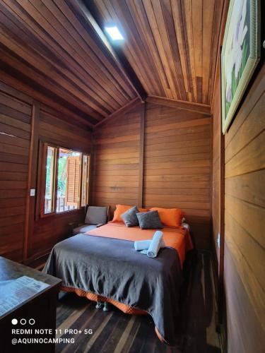 a bedroom with a bed in a wooden room at Aqui no Camping in Brumadinho