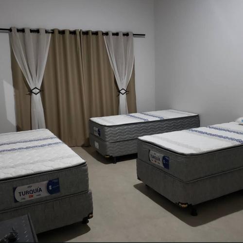 three mattresses sitting in a room with curtains at Casa em Capitolio-MG in Capitólio
