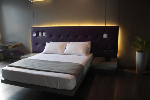 a bedroom with a large bed with a purple headboard at G Hotel by Gaya Group in Santa Cruz de la Sierra