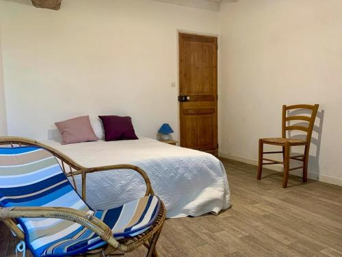 une chambre avec un lit et une chaise dans l'établissement Maison familiale de campagne à 10 min d Utah Beach, à Sainte-Mère-Église