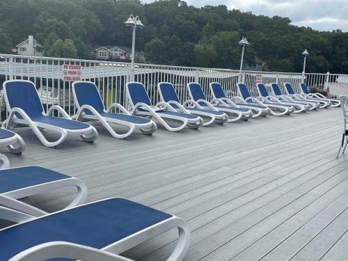 a row of blue and white chairs on a deck at STAIRS OPTIONAL! Lakefront! Pool! On Water! Convenient Fishing! in Osage Beach