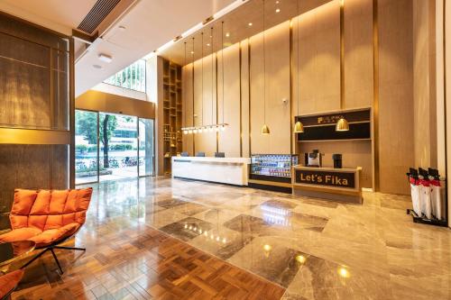 a lobby with an orange chair and a store at Echarm Plus International Hotel Ouzhuang Metro Station Branch - Free Deliver Service to Canton Fair Complex During Canton Fair Period in Guangzhou