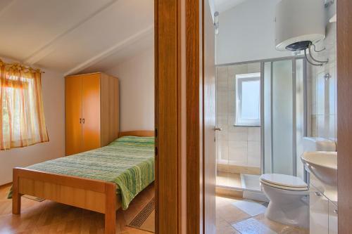 a small bedroom with a bed and a bathroom at Apartmani Tony in Banjole