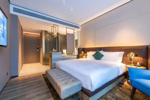 a bedroom with a large bed and a blue chair at Echarm Plus International Hotel Ouzhuang Metro Station Branch - Free Deliver Service to Canton Fair Complex During Canton Fair Period in Guangzhou