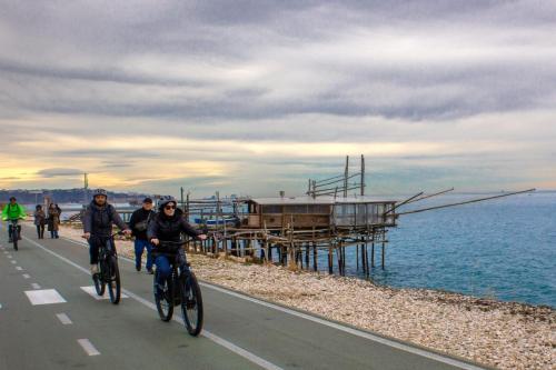 a group of people riding bikes down a road near the ocean at Pescara INN al Golf - Jack Nicklaus in Miglianico