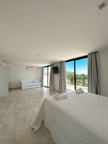 a white bedroom with a large bed and a balcony at La bardot boutique Pousada in Búzios