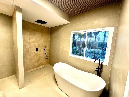 a bathroom with a white tub and a window at Palm Garden Valencia in Bétera