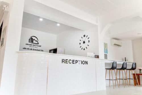 a lobby with a reception counter with a clock and stools at Grand Sattahip Hotel by BSH in Ban Nong Sa