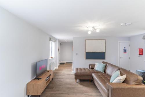 a living room with a couch and a tv at Redwood Escape Stylish New Forest Stay Sleeps 4 Near Paultons Park in Ower