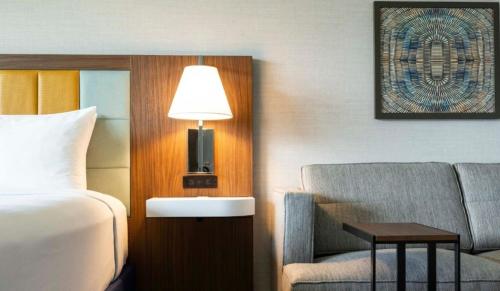 a hotel room with a bed and a couch and a lamp at Hampton Inn & Suites Maui North Shore in Kahului