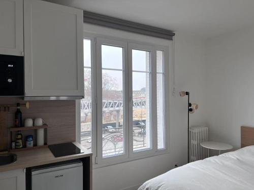une chambre avec un lit et une fenêtre avec un balcon dans l'établissement Studio Plein Soleil Seine, à Paris