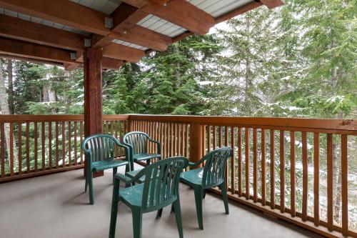 three green chairs on a porch with trees at Horstman House by Whistler Premier in Whistler