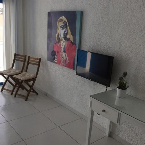 a living room with a tv and a table and a painting at Aphentrika Apartments in Protaras
