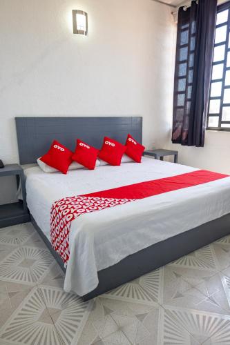 a bedroom with a large bed with red pillows at Hotel Puerta Sur in Comitán