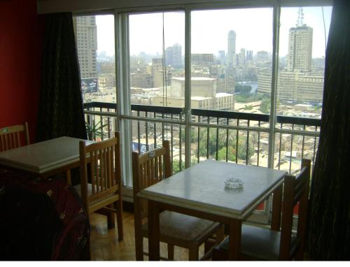 Un balcón con dos mesas y vista a una ciudad. en Isis Hostel 2, en El Cairo