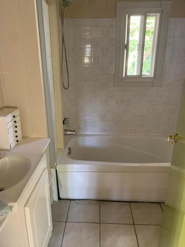 a white bath tub in a bathroom with a window at Secluded Tropical Escape, close to English Harbour in Cobbs Cross