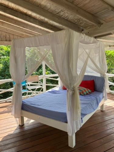 a bed under a canopy on a deck at Secluded Tropical Escape, close to English Harbour in Cobbs Cross