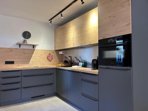 cocina con armarios de madera y microondas negro en Ferienwohnung Lieblingsplatzl mit Garten, en Oberaudorf